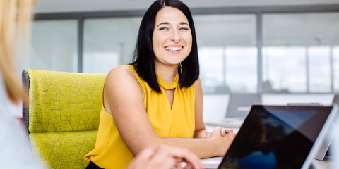 Student sat in chair smiling at another person