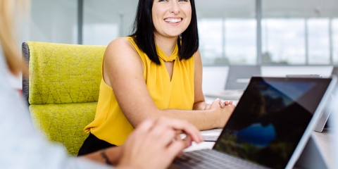 Student sat in chair smiling at another person