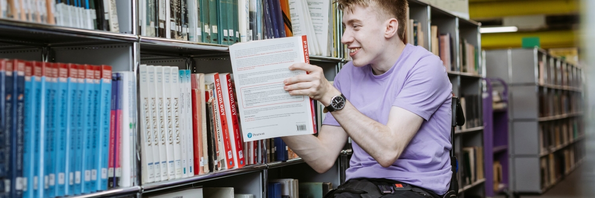 Student removing book from Library bookshelf
