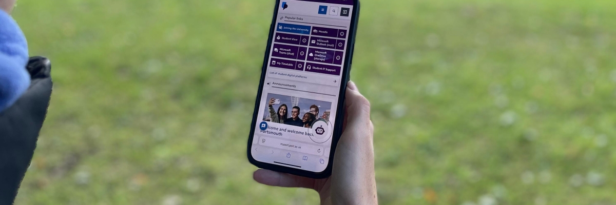 Student holding a mobile device with new MyPort homepage displaying on screen