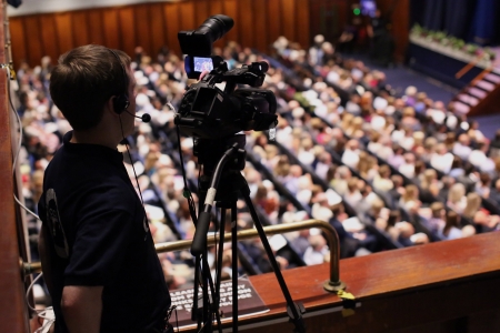 Person filming graduation ceremonies from balcony