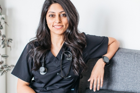 An individual wearing scrubs, seating on a sofa.