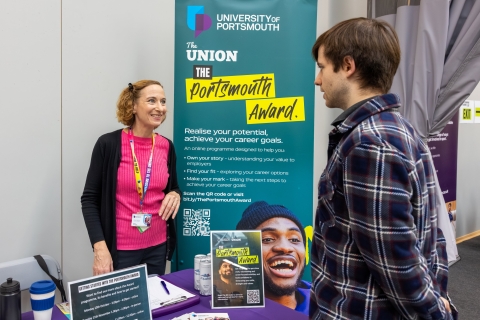 Careers adviser speaking to a student at en events stand