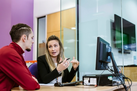 Student and careers advisor talking at a desk with a computer