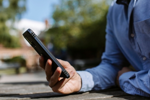Man's hand holding mobile phone, resting on a table