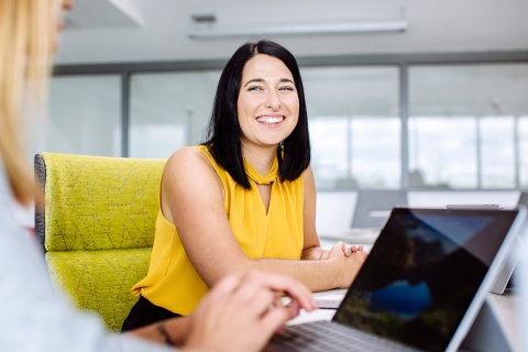 Student sat in chair smiling at another person