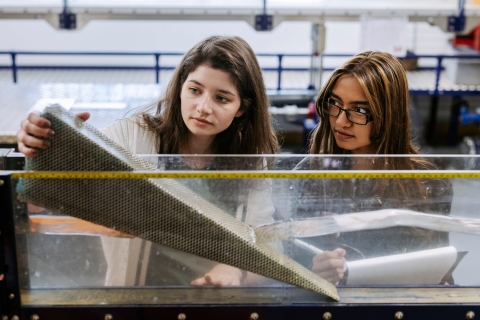 Two female students measuring a project.