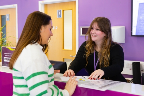 Member of Staff talking to a Student across a desk