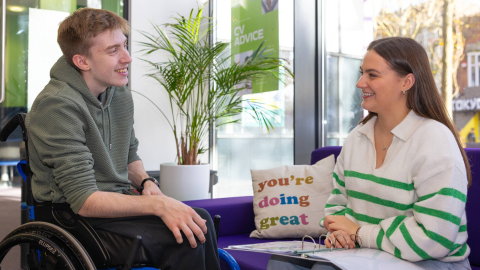 A male student in a wheelchair is speaking to a Careers Officer in the Careers and Employability Centre