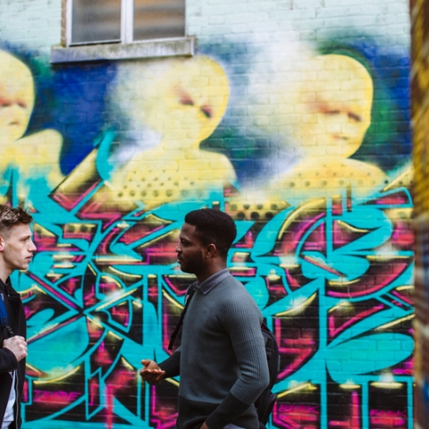 Two students talking in front of graphic painted on wall